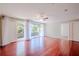 Airy living room boasts red wood floors, a ceiling fan, natural light, and sliding glass door leading to balcony at 601 W Old Hwy 441 # 11B, Mount Dora, FL 32757