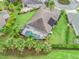 Aerial view of home and a large backyard featuring a screened-in pool and mature tropical landscaping at 631 Independence Path, The Villages, FL 32163