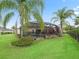 Well-manicured lawn surrounding a screened-in pool and patio area with tropical landscaping at 631 Independence Path, The Villages, FL 32163