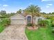 Charming single-story home featuring a paved driveway, attached garage, and tropical landscaping at 631 Independence Path, The Villages, FL 32163