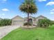 Inviting home with lush lawn, lovely landscaping, brick driveway, and a prominent palm tree at 631 Independence Path, The Villages, FL 32163