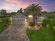 Charming home with landscaped yard, stone driveway, and a beautiful palm tree at dusk at 631 Independence Path, The Villages, FL 32163
