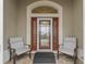 Cozy front porch with decorative glass door, and chairs set up to relax and welcome visitors at 631 Independence Path, The Villages, FL 32163