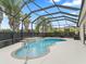 This pool features a waterfall feature and a screened enclosure with tropical landscaping at 631 Independence Path, The Villages, FL 32163