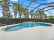 This is an exterior view of a pool with a waterfall feature, set in a screened enclosure at 631 Independence Path, The Villages, FL 32163