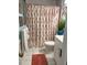 Cozy bathroom with tiled floor, decorative rug, and vibrant orange and white shower curtain at 66 Elmwood Trl, Deland, FL 32724