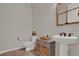 Cozy half-bathroom with wood-look tile flooring, pedestal sink, and charming storage cabinet at 7627 Taormina Way, Clermont, FL 34714