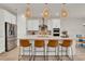 Island kitchen with stainless steel appliances, white cabinets, bar seating, and pendant lighting at 7627 Taormina Way, Clermont, FL 34714