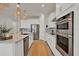 Modern kitchen with stainless appliances, white cabinets, and kitchen island with hanging lights at 7627 Taormina Way, Clermont, FL 34714