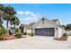 View of the home's 2-car garage and beautifully paved driveway with mature landscaping at 815 Cortez Ave, Lady Lake, FL 32159