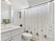 A well-lit bathroom with a white vanity, toilet, and shower featuring a floral curtain at 8779 Se 141St Lane Rd, Summerfield, FL 34491