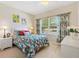 Bright bedroom with floral bedding, light wood floors and a window with natural light at 8779 Se 141St Lane Rd, Summerfield, FL 34491