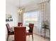 Dining area features a wooden table, red leather chairs, chandelier, and modern patterned curtains at 8779 Se 141St Lane Rd, Summerfield, FL 34491