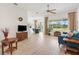Bright living room featuring a ceiling fan, a comfortable blue couch, and large windows overlooking a well-manicured lawn at 8779 Se 141St Lane Rd, Summerfield, FL 34491