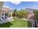 Lush backyard featuring mature palms, vibrant landscaping, brick border, and covered patio with comfortable seating at 898 Abaco Path, The Villages, FL 32163