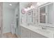 Bright bathroom with double vanity, decorative mirrors, floral wallpaper, and tiled floors at 898 Abaco Path, The Villages, FL 32163