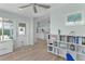 Open floor plan featuring hard wood floors, bookshelf, and view of the kitchen with white cabinets and appliances at 898 Abaco Path, The Villages, FL 32163