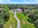 Expansive aerial view of a lush, tree-lined property featuring a home with a red roof and long driveway at 9023 Silver Lake Dr, Leesburg, FL 34788