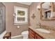 Bathroom vanity featuring granite countertops, wood cabinets, decorative mirror, and window providing natural light at 9023 Silver Lake Dr, Leesburg, FL 34788