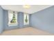 Bright bedroom with light blue walls, carpet floors, and two windows dressed with white curtains at 9023 Silver Lake Dr, Leesburg, FL 34788