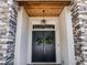 Elegant stone entryway with double doors, statement lighting, and a charming wood ceiling at 9518 Mid Summer Ln, Leesburg, FL 34788