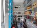 Well-organized walk-in pantry with white wire shelving with cleaning supplies, ladders, and boxes at 9518 Mid Summer Ln, Leesburg, FL 34788