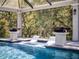 Beautiful pool featuring lounge seating within the pool and landscaping providing a natural backdrop at 9518 Mid Summer Ln, Leesburg, FL 34788