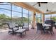 Screened patio featuring brick pavers, comfortable seating, ceiling fans, and an outdoor dining area with a grill at 453 Treviso Dr, Poinciana, FL 34759