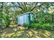 Backyard storage shed surrounded by lush, tropical landscaping with lots of mature foilage at 1007 N Shore Dr, Leesburg, FL 34748
