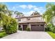 Stately home featuring stone accents, a tile roof, and a spacious driveway with a three-car garage at 10122 Royal Island Ct, Orlando, FL 32836