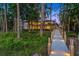 Stunning waterfront home with a lighted wooden walkway through a lush green lawn and mature trees, and inviting architectural details at 10122 Royal Island Ct, Orlando, FL 32836