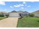 Charming single-story home with a two-car garage, blue shutters, and a well-manicured lawn at 11287 Stewart Loop, Oxford, FL 34484