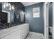 Bathroom with double sinks, tile accent wall, and marble floor at 12833 Hyland Ln, Clermont, FL 34711