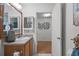 A bathroom vanity area with a mirror and sink leading to an open doorway, with wood floors at 1291 Jonesville Ter, The Villages, FL 32162