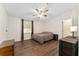 Bright bedroom featuring wood-look floors, ceiling fan, and a window with light brown curtains at 1303 E Schwartz Blvd, Lady Lake, FL 32159