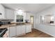 Bright kitchen features white cabinets, modern appliances, and a window overlooking the living area at 1303 E Schwartz Blvd, Lady Lake, FL 32159