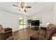 Cozy living room with wood floors, ceiling fan, and sliding glass door to the outdoor space at 1303 E Schwartz Blvd, Lady Lake, FL 32159