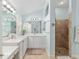 Bathroom featuring a double vanity with marble countertops, white cabinets, and a tiled glass-enclosed shower at 1521 Southport St, The Villages, FL 32162