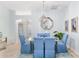 Elegant dining room with a glass-top table, blue upholstered chairs, and stylish lighting fixture at 1521 Southport St, The Villages, FL 32162