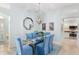 Dining room with glass table, blue chairs, unique light fixture, and views to the kitchen at 1521 Southport St, The Villages, FL 32162