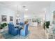 Open concept dining area with a glass-top table and blue chairs flows into the spacious living room at 1521 Southport St, The Villages, FL 32162