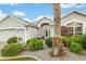 Inviting front entrance with a well-manicured lawn, palm tree, and elegant landscaping at 1521 Southport St, The Villages, FL 32162