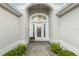 Elegant front entrance with a decorative glass door and a neatly paved walkway lined with green shrubbery at 1521 Southport St, The Villages, FL 32162