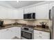 Well-lit kitchen featuring stainless steel appliances, granite countertops, and white cabinetry at 1521 Southport St, The Villages, FL 32162