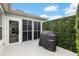 Outdoor patio area with covered grill, screened lanai, and mature privacy hedge at 1521 Southport St, The Villages, FL 32162