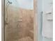 Tiled walk-in shower featuring a built-in bench and glass door, along with towel bars at 1521 Southport St, The Villages, FL 32162