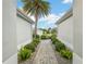 Paver walkway lined with bushes lead to a charming home with a palm tree in the front yard at 1521 Southport St, The Villages, FL 32162