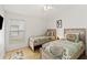 Cozy bedroom featuring two twin beds with patterned bedding, a window, and blond wood flooring at 157 Julliard Blvd, Davenport, FL 33897