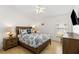 Comfortable bedroom with a wooden bed frame, patterned bedding, two nightstands, lamps, and blond wood floors at 157 Julliard Blvd, Davenport, FL 33897