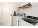 Functional laundry room featuring a white washer and dryer, shelving, and access to the exterior at 157 Julliard Blvd, Davenport, FL 33897